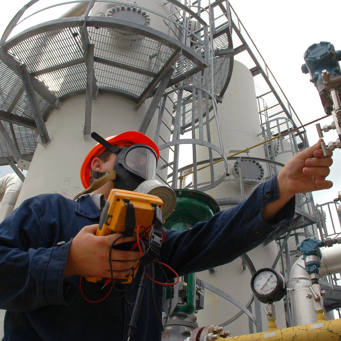 The worker in a gas mask looks at a manometer of the gas refinery